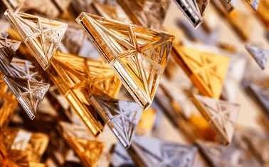 Abstract 3D rendering of metallic triangular prisms in gold, silver, and bronze tones, suspended in a dynamic, geometric pattern. Modern digital art concept with a futuristic and architectural design
