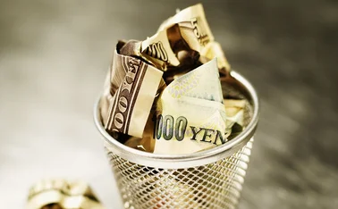 Yen and dollars in wastepaper basket