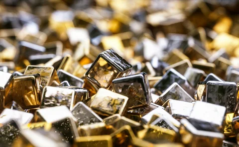 Close-up of glossy metallic gold and silver cubes with reflective surfaces, scattered in a dynamic and abstract arrangement