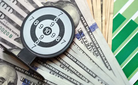 Dollar notes on a financil chart overlaid with a miniature target