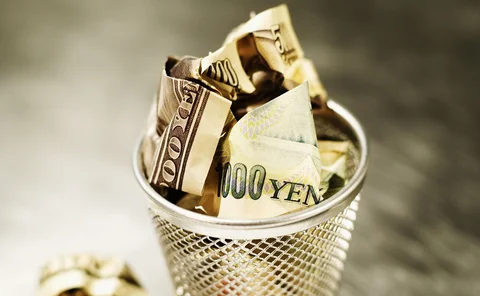 Yen and dollars in wastepaper basket