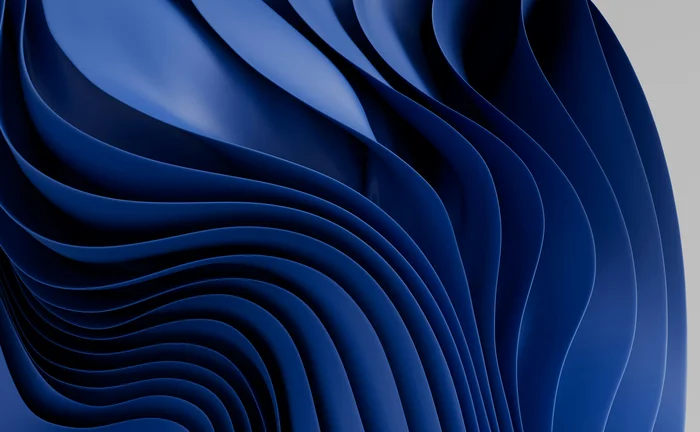 A deep, saturated blue abstract background featuring numerous smooth, flowing, wave-like layers or folds, reminiscent of fabric or liquid, set against a plain light gray background on the right