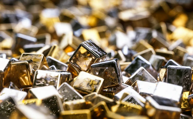 Close-up of glossy metallic gold and silver cubes with reflective surfaces, scattered in a dynamic and abstract arrangement