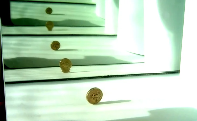 Close-up of a British pound coin infinitely reflected between two mirrored surfaces showing light reflections