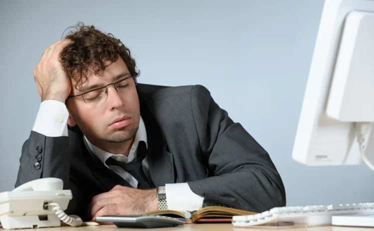 A bored businessman asleep in front of his computer