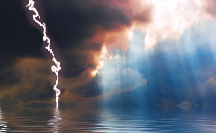 Dark storm clouds and lightning broken by the sun shining down onto a calm sea 