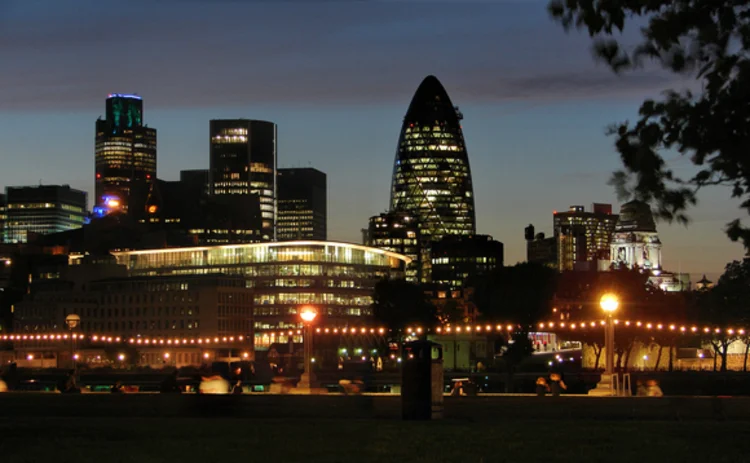 London skyscrapers with sun descending and building lights on