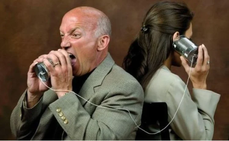 A man screaming into a tin-can telephone while a woman listens on the other end of the line