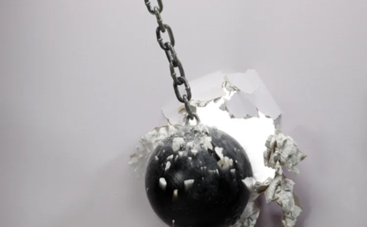 A wrecking ball breaking a white wall A wrecking ball breaking a white wall