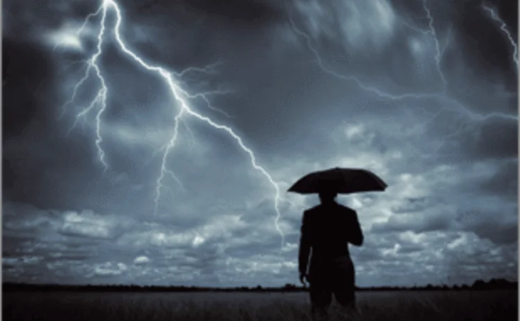 A man with an umbrella sheltering from a thunderstorm