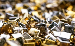 Close-up of glossy metallic gold and silver cubes with reflective surfaces, scattered in a dynamic and abstract arrangement
