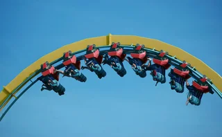 People hang upside down at the top section of a rollercoaster