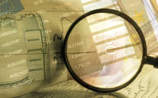 Magnifying glass examining FX crosses against backdrop of foreign currency